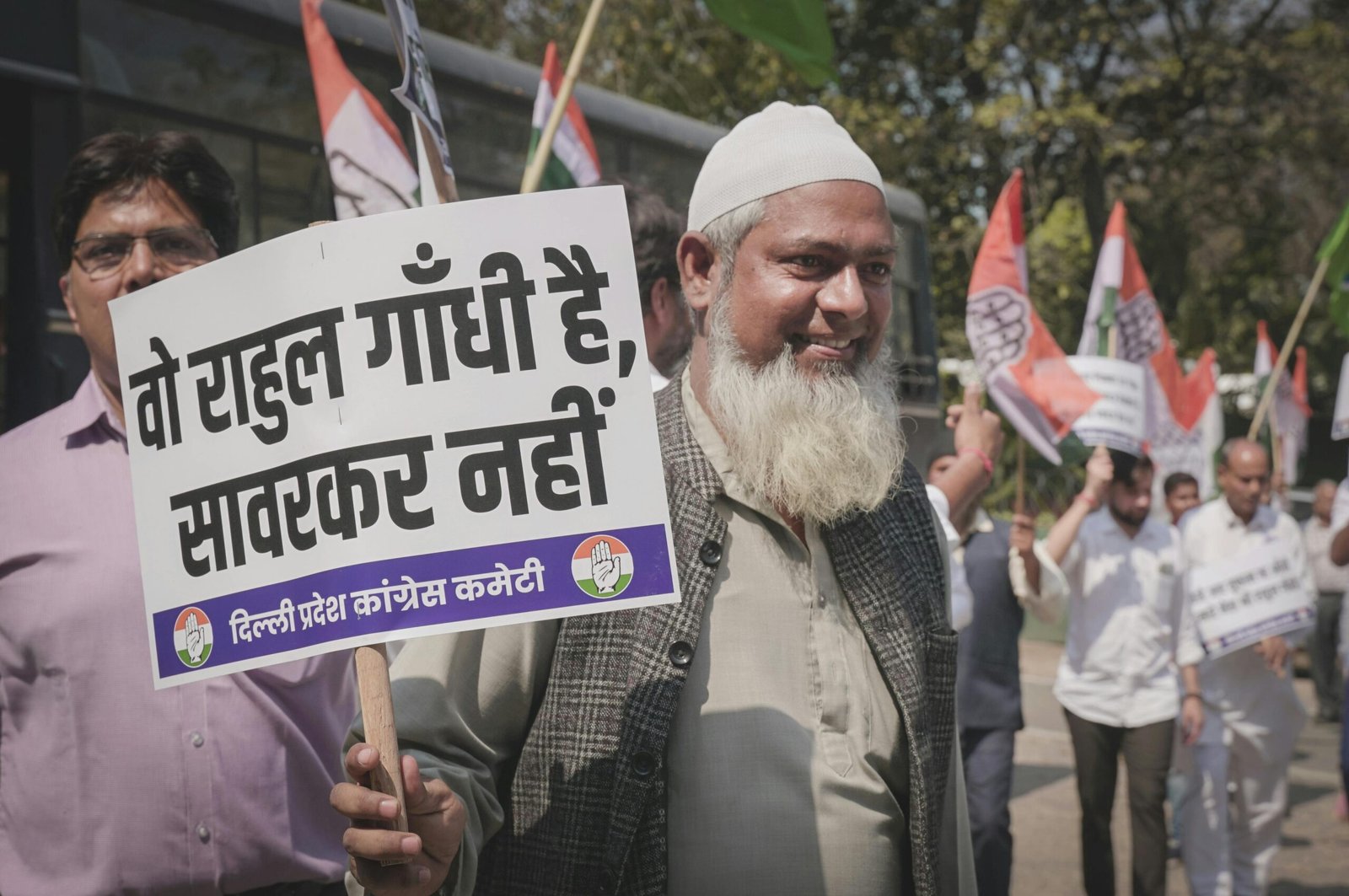 A man participates in a street protest holding a sign with political messaging.
